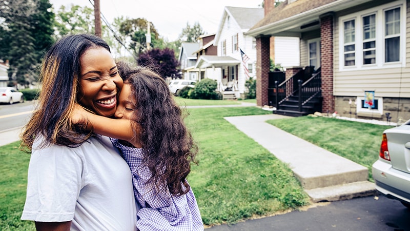 Family embracing outside a home